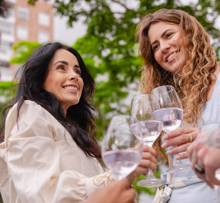 Um grupo celebra com taças, com duas mulheres em destaque